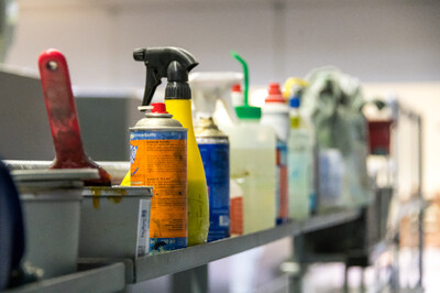 Mehrere Sprüh- und Reinigungsflaschen stehen in einer Reihe in einer Druckerei.